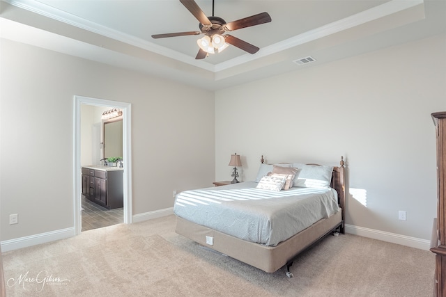 carpeted bedroom featuring crown molding, ensuite bath, a raised ceiling, and ceiling fan