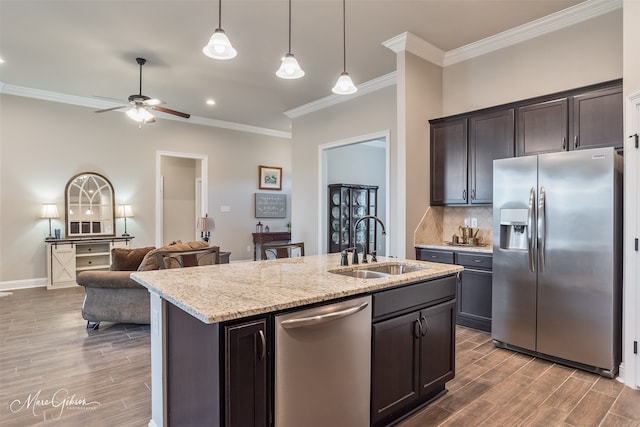 kitchen featuring dark brown cabinetry, sink, hanging light fixtures, stainless steel appliances, and a kitchen island with sink