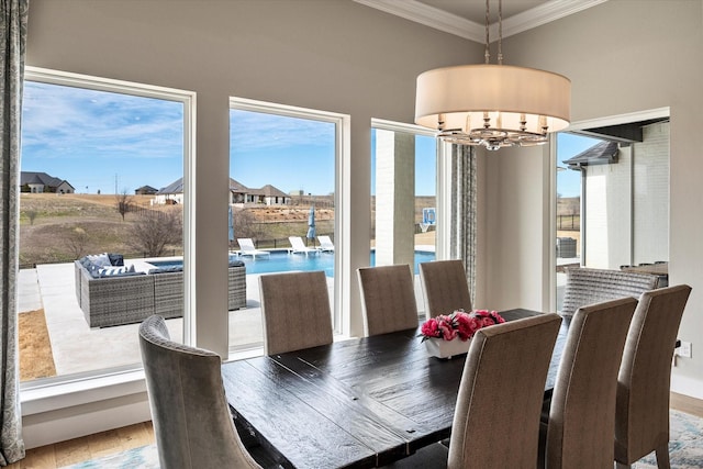 dining area with crown molding, wood finished floors, and an inviting chandelier