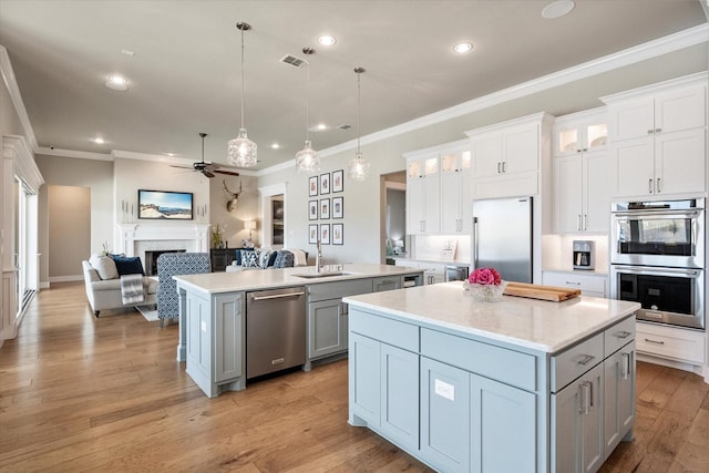 kitchen with a center island with sink, open floor plan, stainless steel appliances, a fireplace, and a sink