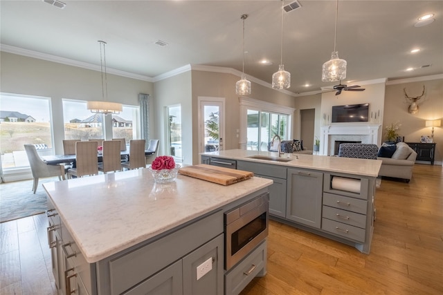 kitchen with a kitchen island, sink, stainless steel microwave, and decorative light fixtures