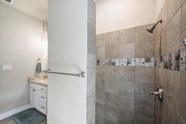 bathroom with visible vents, vanity, tile patterned flooring, tiled shower, and baseboards