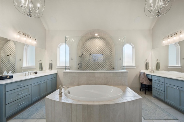 full bath featuring an inviting chandelier, a garden tub, vaulted ceiling, and two vanities