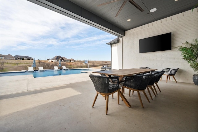 view of patio / terrace featuring outdoor dining space, a ceiling fan, and an outdoor pool