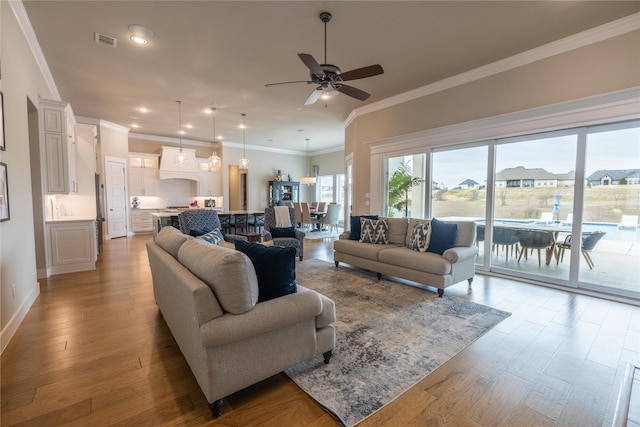 living room with crown molding, light hardwood / wood-style flooring, and ceiling fan