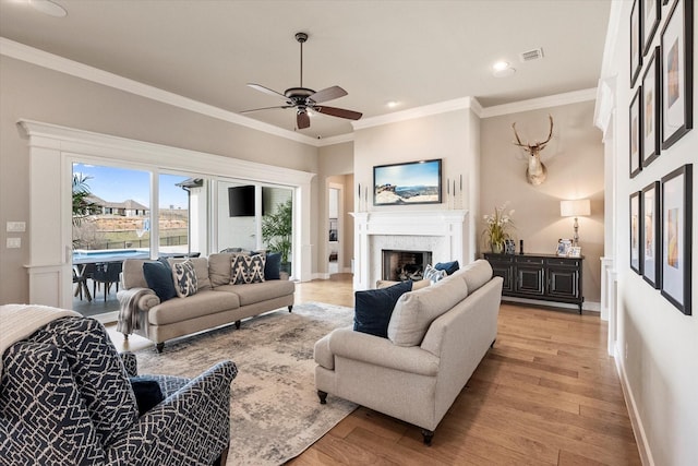 living room with light wood finished floors, a fireplace, and crown molding