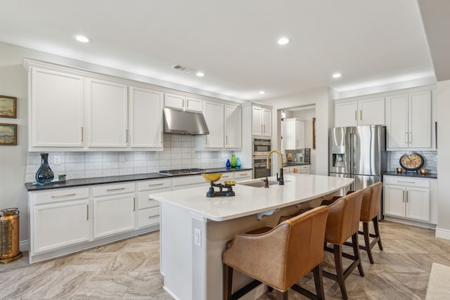 kitchen featuring white cabinetry, an island with sink, appliances with stainless steel finishes, and a breakfast bar area