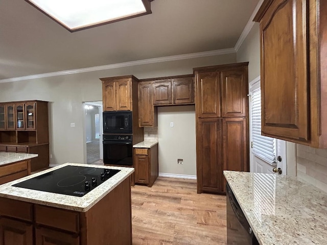 kitchen featuring backsplash, black appliances, crown molding, light stone countertops, and light hardwood / wood-style flooring