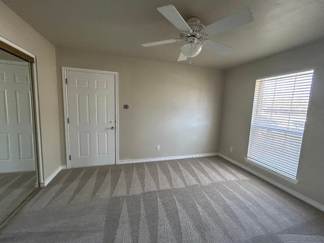 unfurnished room with ceiling fan and carpet