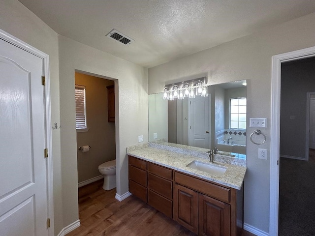 bathroom featuring wood-type flooring, toilet, a bath, and vanity