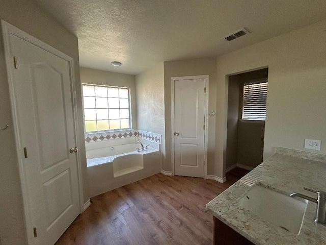 bathroom featuring vanity, a bathing tub, wood-type flooring, and a textured ceiling