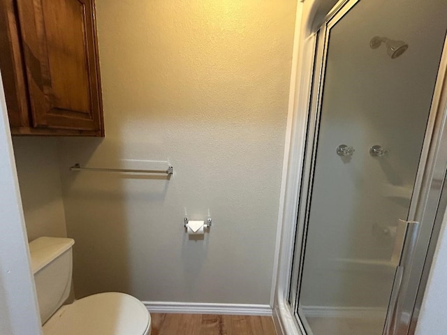 bathroom featuring an enclosed shower, wood-type flooring, and toilet