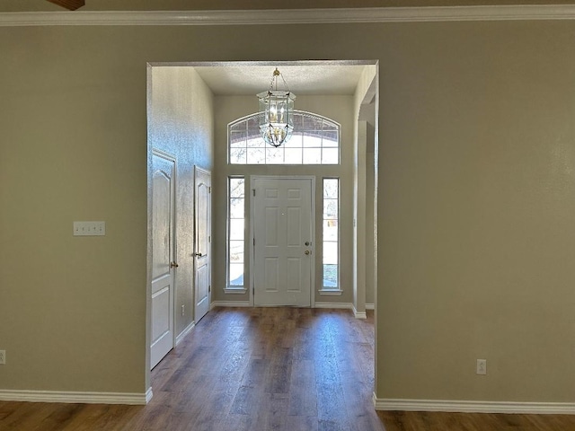 foyer entrance with crown molding, hardwood / wood-style floors, and an inviting chandelier