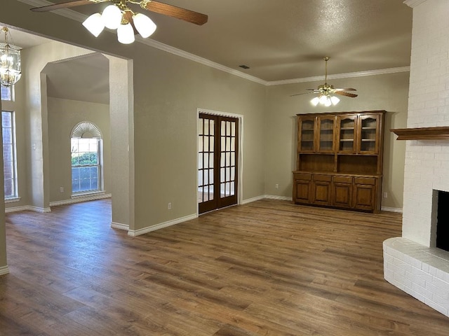 unfurnished living room with crown molding, dark wood-type flooring, a fireplace, and ceiling fan