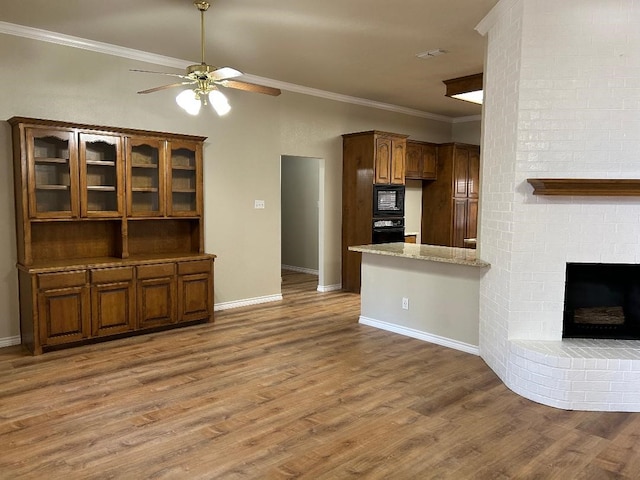 unfurnished living room with hardwood / wood-style flooring, ceiling fan, ornamental molding, and a brick fireplace