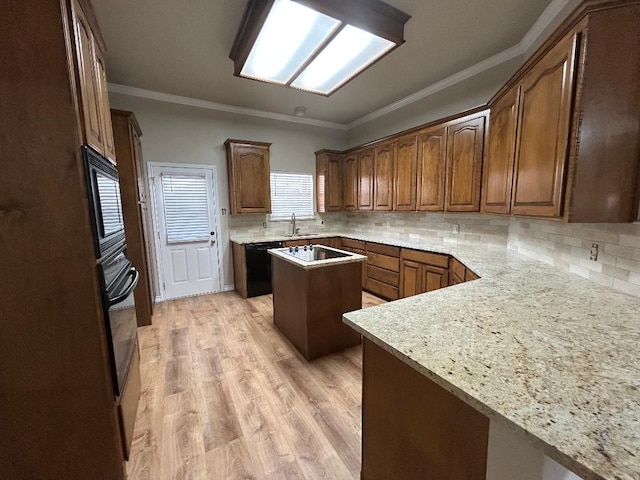 kitchen with decorative backsplash, ornamental molding, a center island, light stone counters, and black appliances