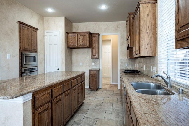 kitchen featuring light stone counters, sink, decorative backsplash, and stainless steel appliances