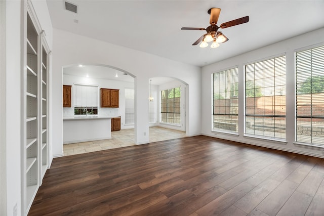 9328 Old Veranda Rd, Plano, TX 75024 - unfurnished living room with wood finished floors, a ceiling fan, arched walkways, baseboards, and a sink