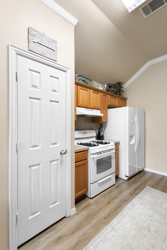 kitchen with ornamental molding, lofted ceiling, light wood-type flooring, and white appliances