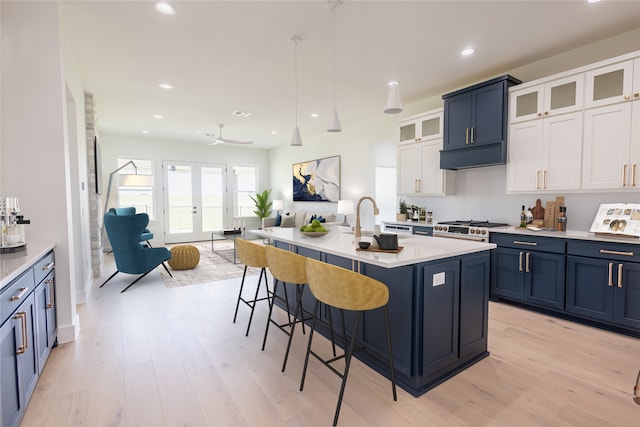 kitchen featuring hanging light fixtures, a kitchen bar, white cabinets, and a center island with sink