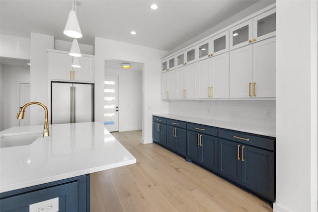 kitchen featuring sink, white cabinetry, blue cabinets, decorative light fixtures, and high end refrigerator