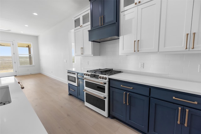 kitchen with tasteful backsplash, double oven range, blue cabinets, and white cabinets