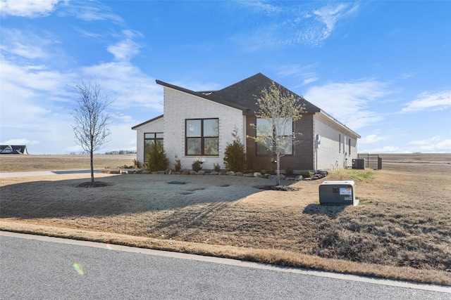 view of front of property with central AC and a front lawn