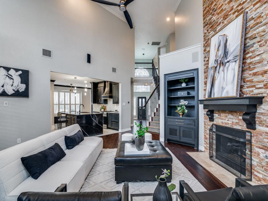 living room with wood-type flooring, a stone fireplace, sink, and built in features