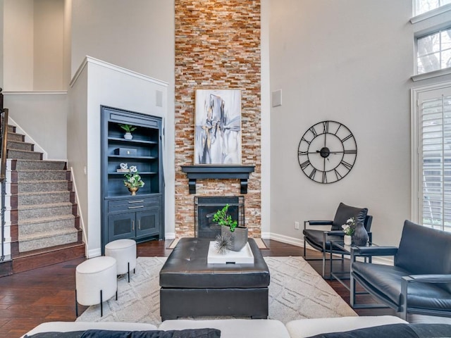 living room with a high ceiling, dark hardwood / wood-style flooring, a fireplace, and built in shelves