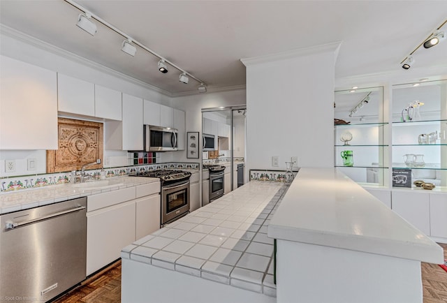 kitchen featuring dark parquet flooring, appliances with stainless steel finishes, and white cabinets