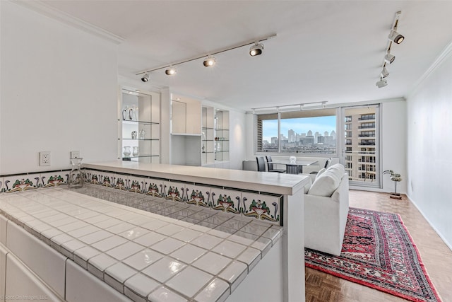 kitchen featuring tile counters, ornamental molding, white cabinets, parquet floors, and kitchen peninsula