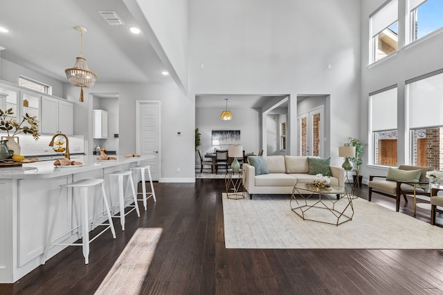 living room featuring dark wood-type flooring, sink, and a towering ceiling