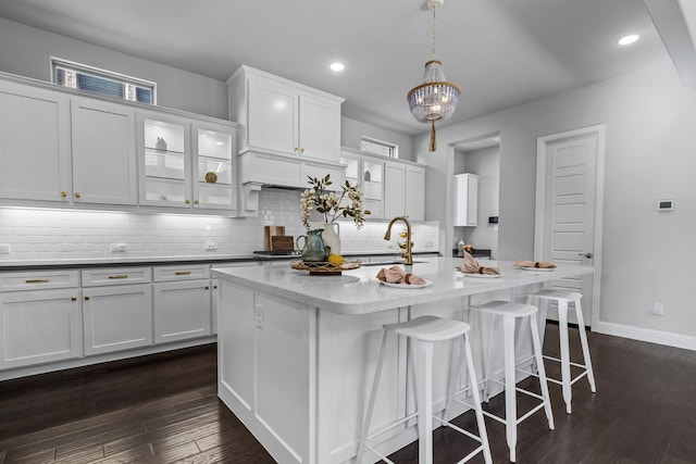 kitchen featuring pendant lighting, sink, a kitchen island with sink, and white cabinets