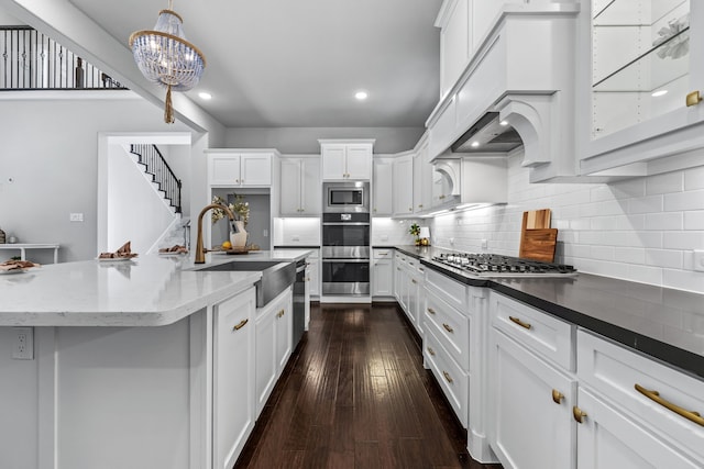 kitchen with sink, appliances with stainless steel finishes, hanging light fixtures, white cabinets, and dark stone counters