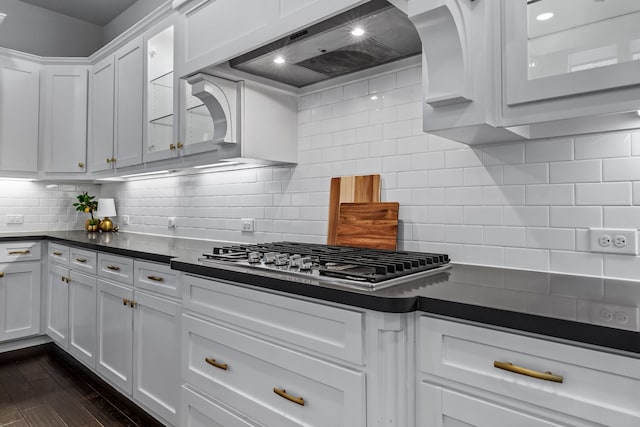 kitchen with custom range hood, stainless steel gas cooktop, white cabinets, dark hardwood / wood-style flooring, and decorative backsplash