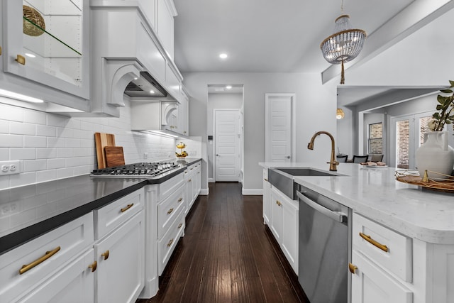 kitchen featuring sink, appliances with stainless steel finishes, white cabinetry, dark hardwood / wood-style floors, and decorative light fixtures