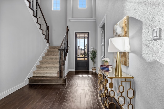 foyer entrance with hardwood / wood-style flooring, a towering ceiling, and plenty of natural light