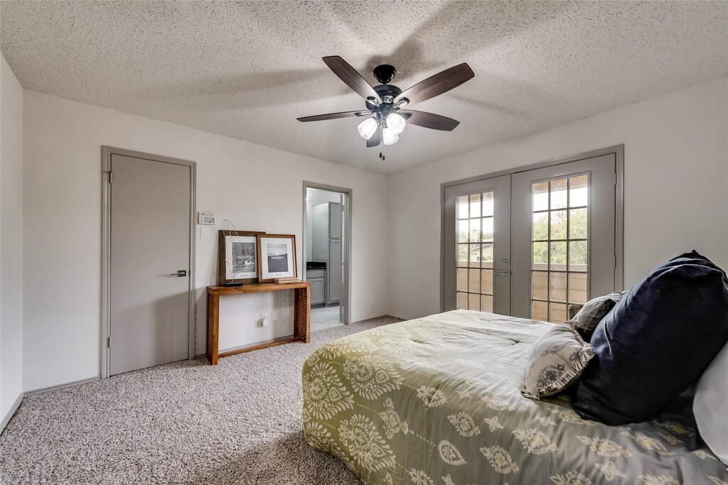 bedroom with light carpet, a ceiling fan, a textured ceiling, and french doors