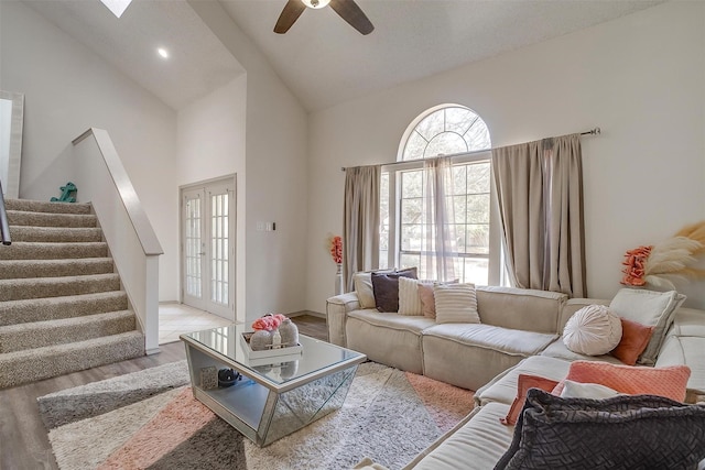 living area with high vaulted ceiling, wood finished floors, a ceiling fan, stairs, and french doors