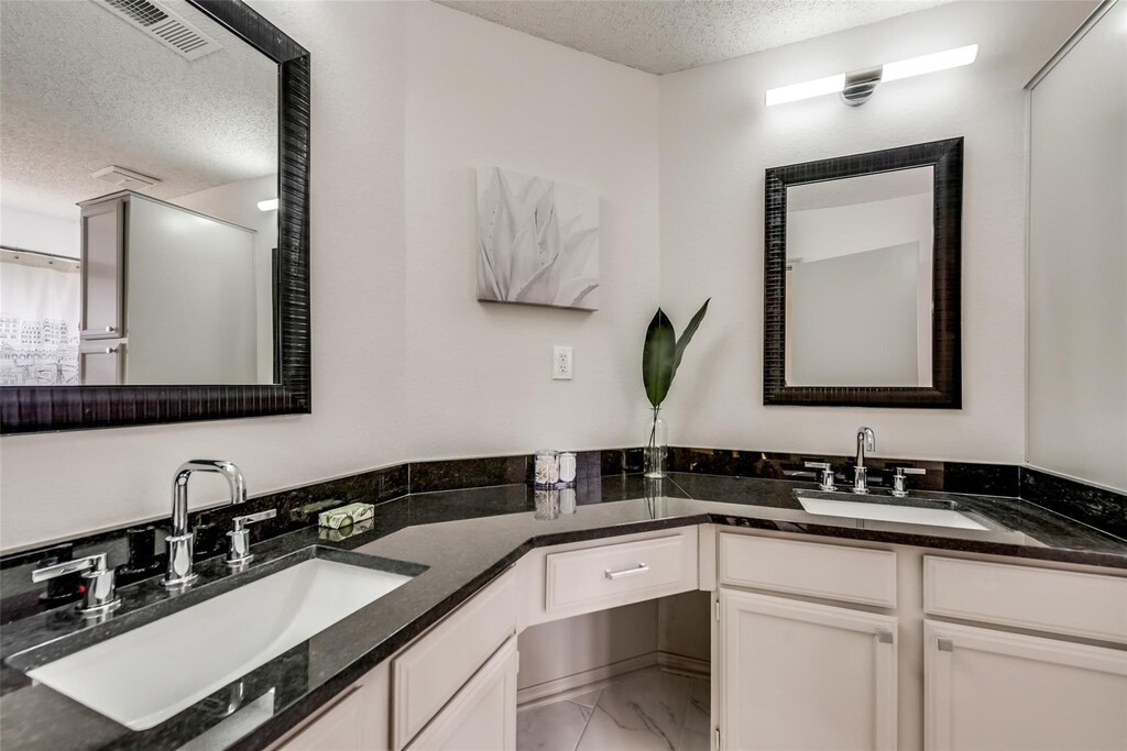 full bath with marble finish floor, a sink, a textured ceiling, and walk in shower