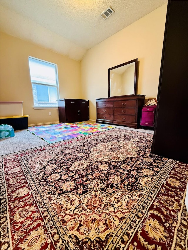 bedroom with lofted ceiling, carpet floors, and a textured ceiling