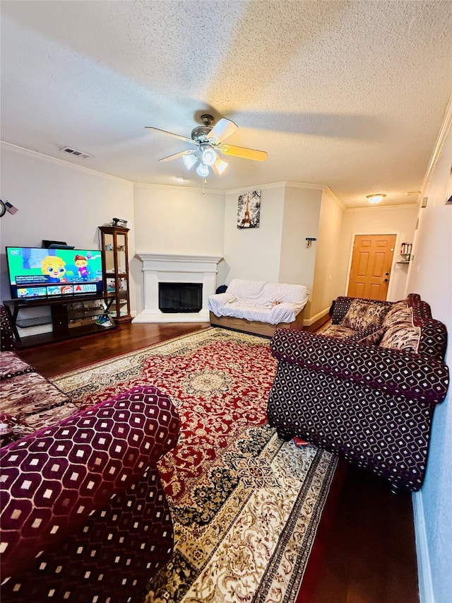 living room with ceiling fan, ornamental molding, hardwood / wood-style floors, and a textured ceiling