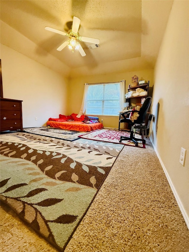 carpeted bedroom featuring lofted ceiling, ceiling fan, and a tray ceiling