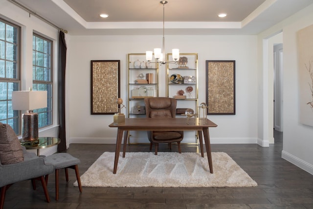 office space with dark hardwood / wood-style flooring, a tray ceiling, and an inviting chandelier