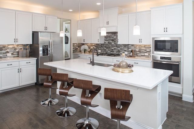 kitchen featuring white cabinetry, hanging light fixtures, stainless steel appliances, and sink