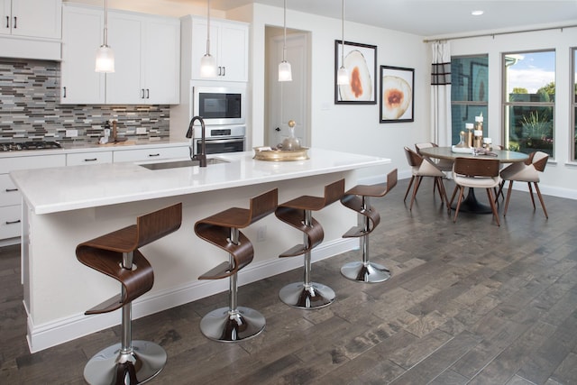 kitchen featuring white cabinetry, appliances with stainless steel finishes, a kitchen island with sink, and pendant lighting