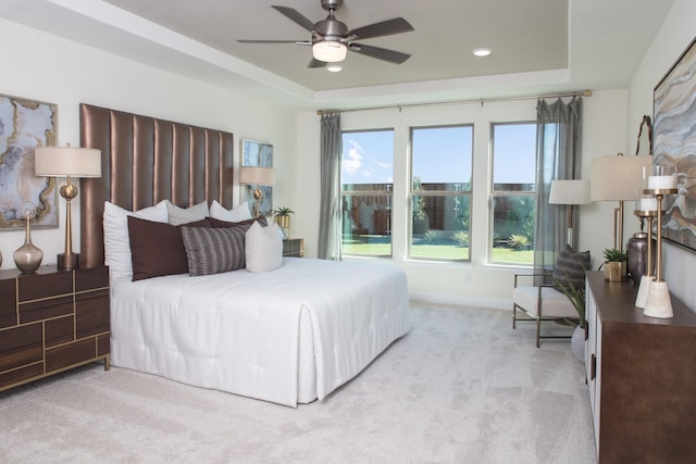 carpeted bedroom featuring a raised ceiling and ceiling fan