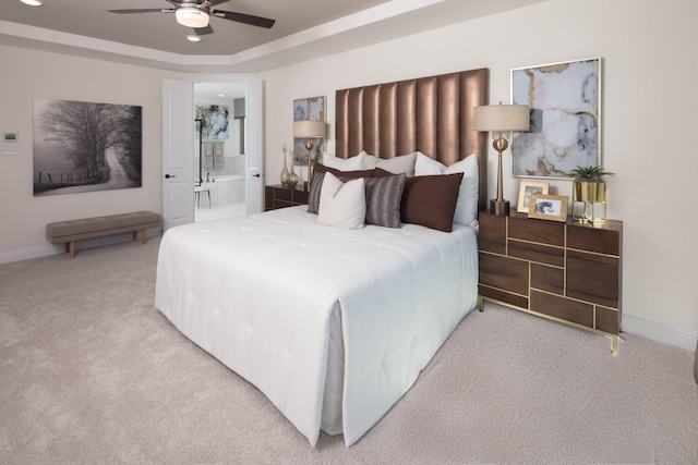 bedroom featuring ceiling fan, connected bathroom, carpet flooring, and a raised ceiling