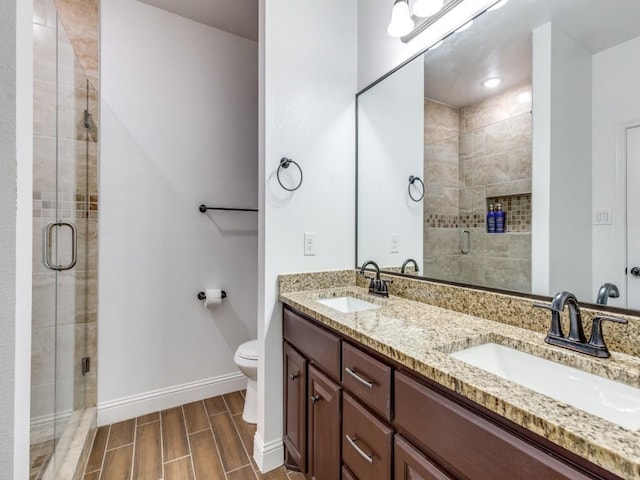 bathroom featuring a shower with door, vanity, and toilet