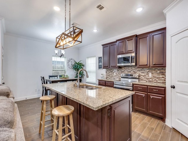 kitchen featuring tasteful backsplash, sink, hanging light fixtures, ornamental molding, and stainless steel appliances